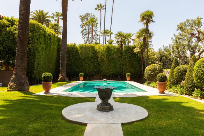 Hedges and palm trees surround the pool.