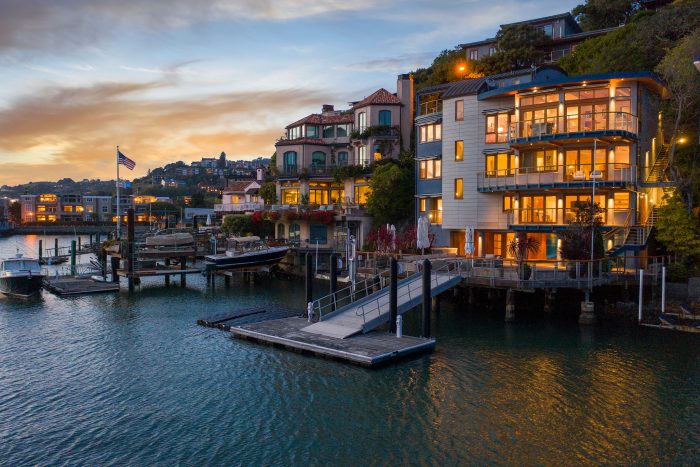 View looking up from the water of the home illuminated before sunset.