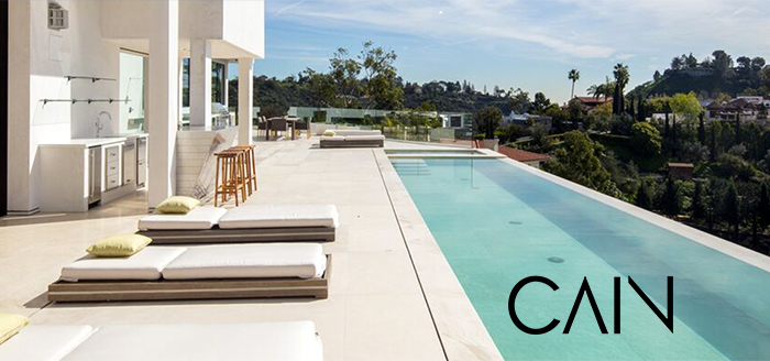 Modern designed rectangle pool with modern pool-side furnishings designed by Cain Interiors and Construction with logo