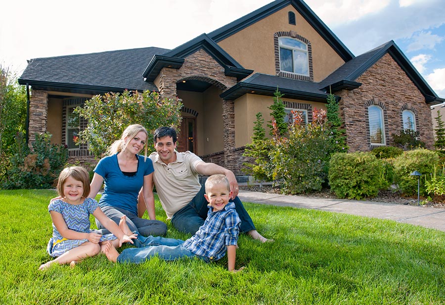 Smiling family on front lawn of a house