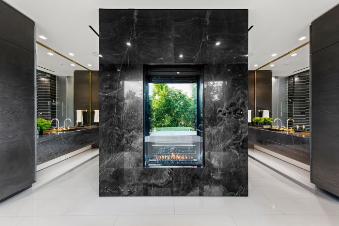 An elegant primary suite features a black-marble encased shower with fireplace.