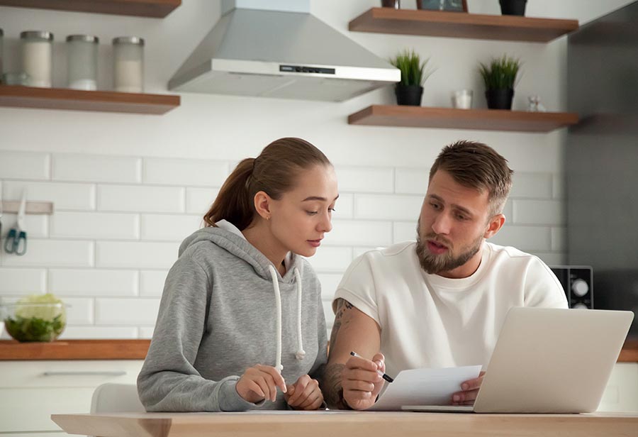 Focused serious couple checking bills sitting together at kitche
