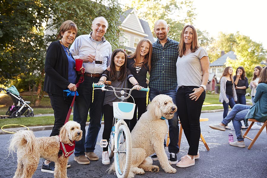 Neighbours with pet dogs smiling to camera at a block party