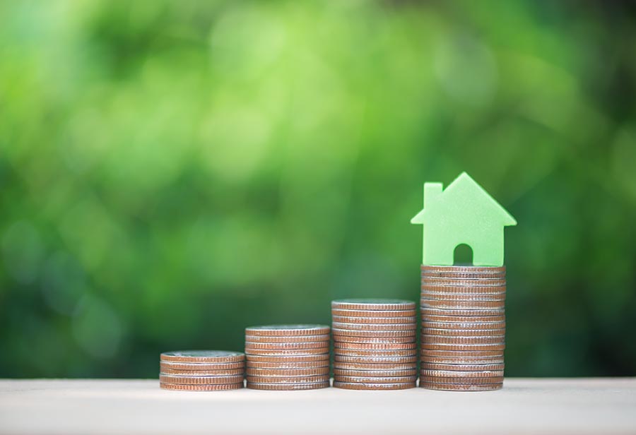 Home model on the growing coin stack for concept of money saving for home buying fund