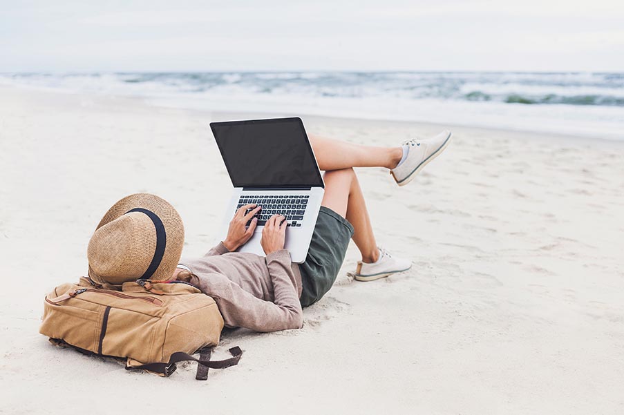 Young woman using laptop on a beach